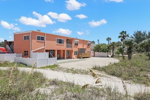 A multi-story building with a flat roof, a covered patio, and a sandy ground area. - 🌅 Birdsong #26 — Just Steps to the Sand from this Treasure Island Delite (Treasure Island)