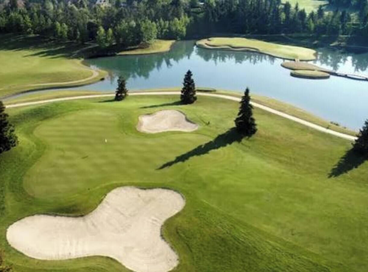 A golf course with sand bunkers, water hazards, and trees.