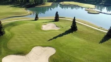 A golf course with sand bunkers, water hazards, and trees.