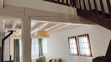 En rummelig opholdsstue med højt til loftet, en trappe i træ og en modulopbygget sofa.