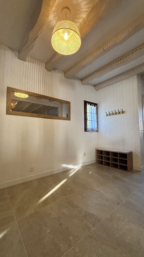 A spacious room with a large mirror, a window with curtains, a ceiling light fixture, and a built-in shelf.