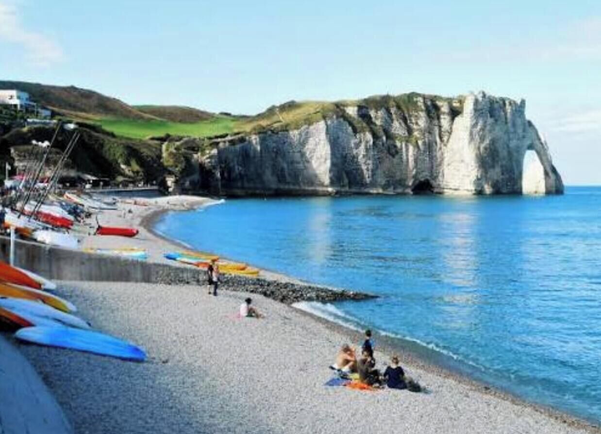 A beach with kayaks, a rocky cliff, and a clear blue sky.