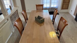 A dining room with a long wooden table, six wooden chairs, a woven basket, and a hanging light fixture.