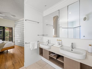 Een moderne badkamer met een grote spiegel, twee wasbakken en een douche.