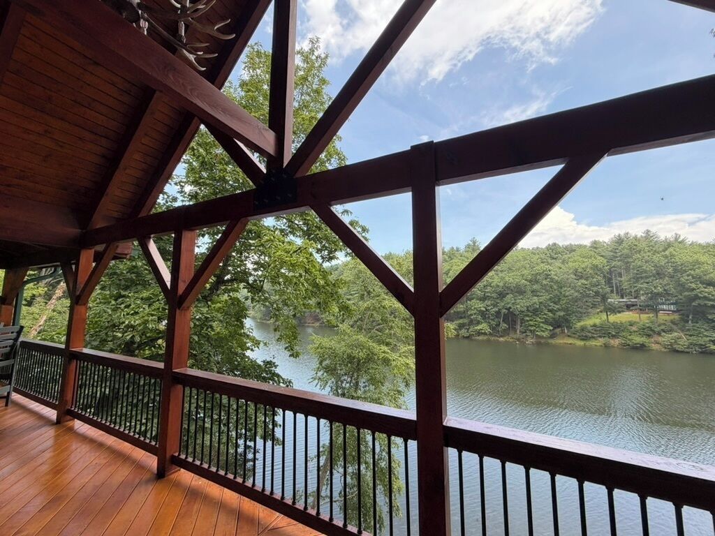Une terrasse en bois avec une rambarde donnant sur un lac et une zone boisée.