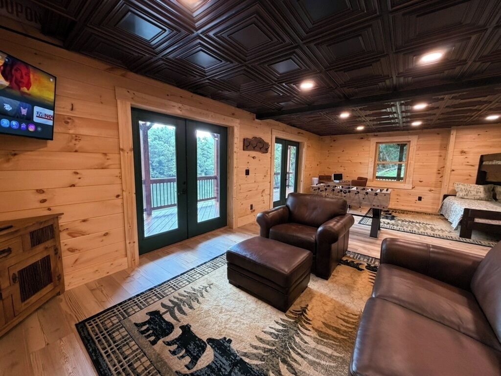 A wooden interior with a fireplace, leather sofas, and a television mounted on the wall.