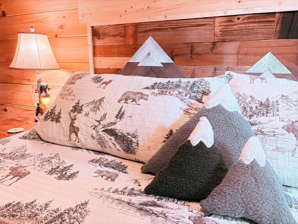 Un lit avec de nombreux oreillers, chacun orné de motifs représentant des animaux sauvages.