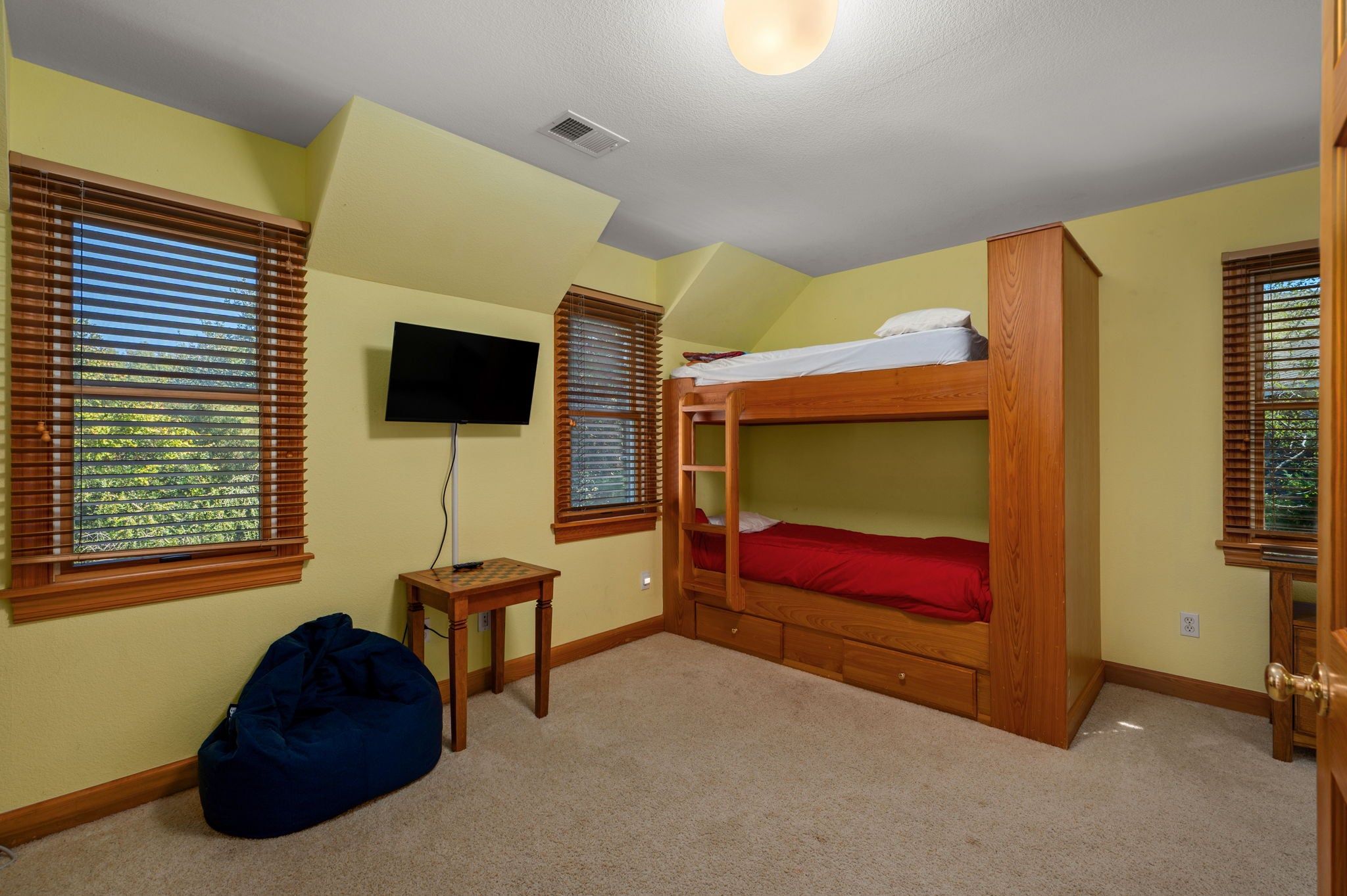 A room with bunk beds, a television, and a bean bag chair.