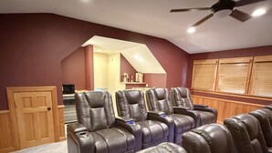 A home theater room with leather reclining chairs, a ceiling fan, and a wooden door. - Beach ParTee Time: Soundfront, Private Pool, Hot Tub, Community Amenities (Corolla)