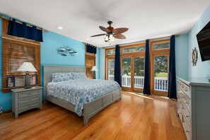 A bedroom with a bed, nightstands, a ceiling fan, and large windows. - Beach ParTee Time: Soundfront, Private Pool, Hot Tub, Community Amenities (Corolla)
