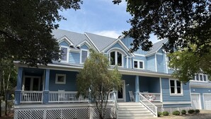 A two-story house with a front porch, a covered entryway, and a visible garage. - Beach ParTee Time: Soundfront, Private Pool, Hot Tub, Community Amenities (Corolla)