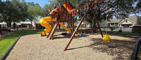Un parque infantil con tobogán, columpios y estructura para escalar.