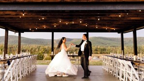 A wedding ceremony in a covered outdoor area with tables set for guests, surrounded by natural scenery. - River Cabin with Pickleball and Kayaks (Smithville)