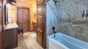 A wooden interior with a bathtub, a door with antlers, and a stone wall.