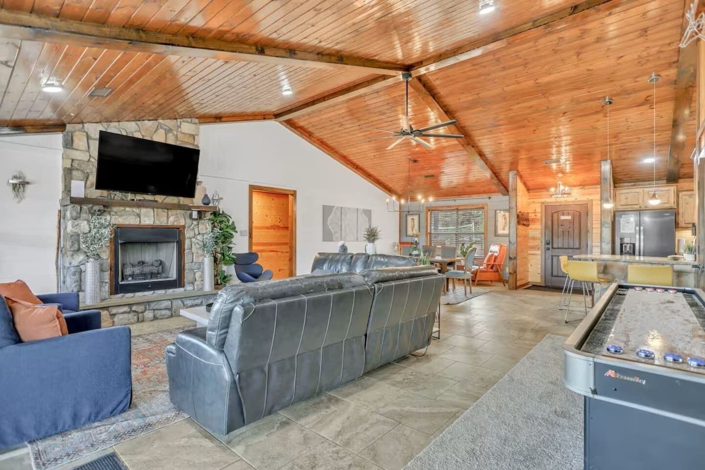 A spacious living area with a stone fireplace, a large gray sectional sofa, and a pool table.