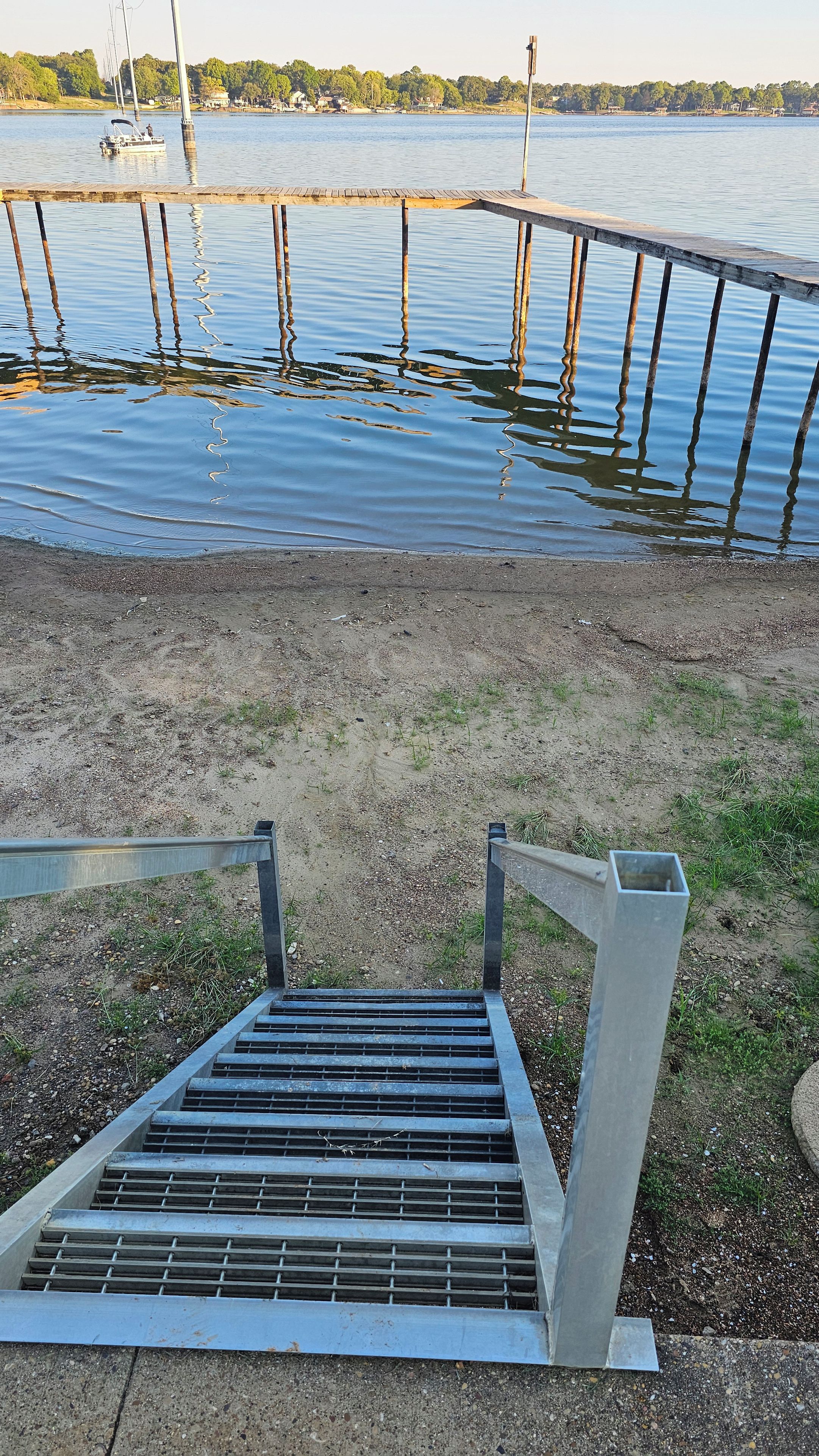 A metal staircase leading to a dock over a calm body of water.