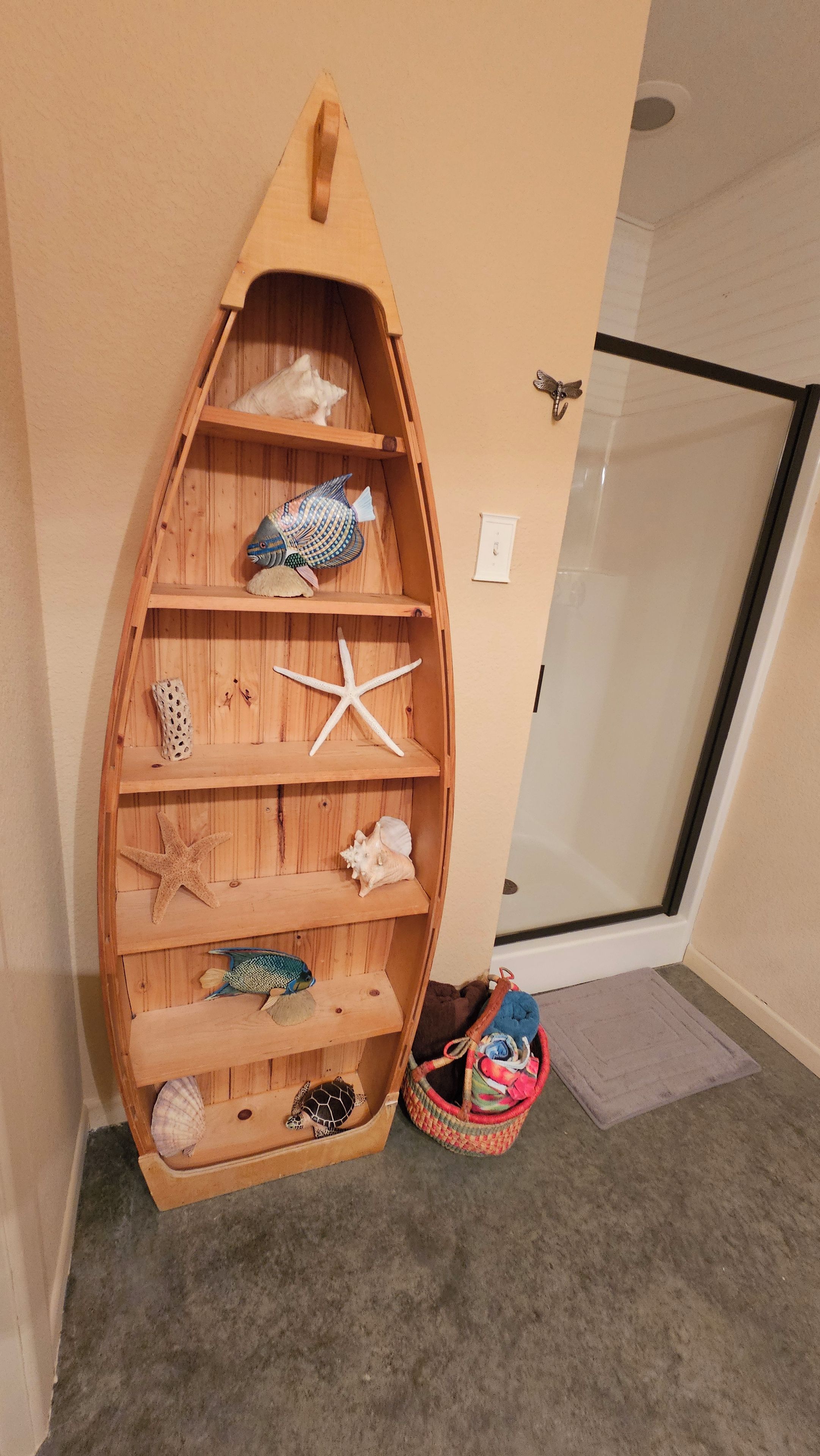 Une étagère en bois, en forme de bateau, agrémentée de divers objets décoratifs.