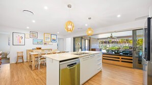 Uma cozinha moderna com ilha central, piso de madeira e iluminação pendente.