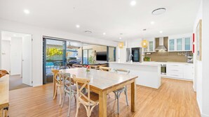 Uma cozinha moderna com armários brancos, uma ilha central e uma área de refeições com móveis de madeira.