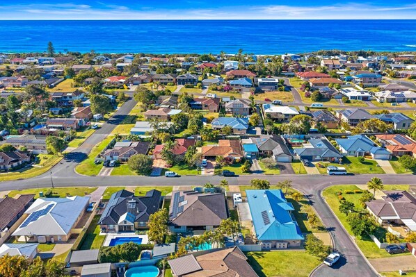 A residential area with houses, roads, and a view of the ocean.