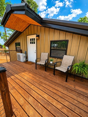 A wooden deck with two chairs and a table, a door, and a window.