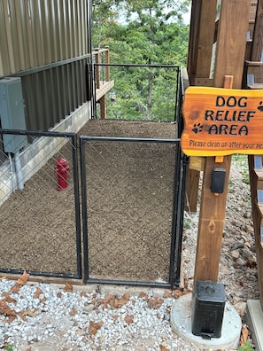 A fenced dog relief area with a sign requesting visitors to clean up after their pets.