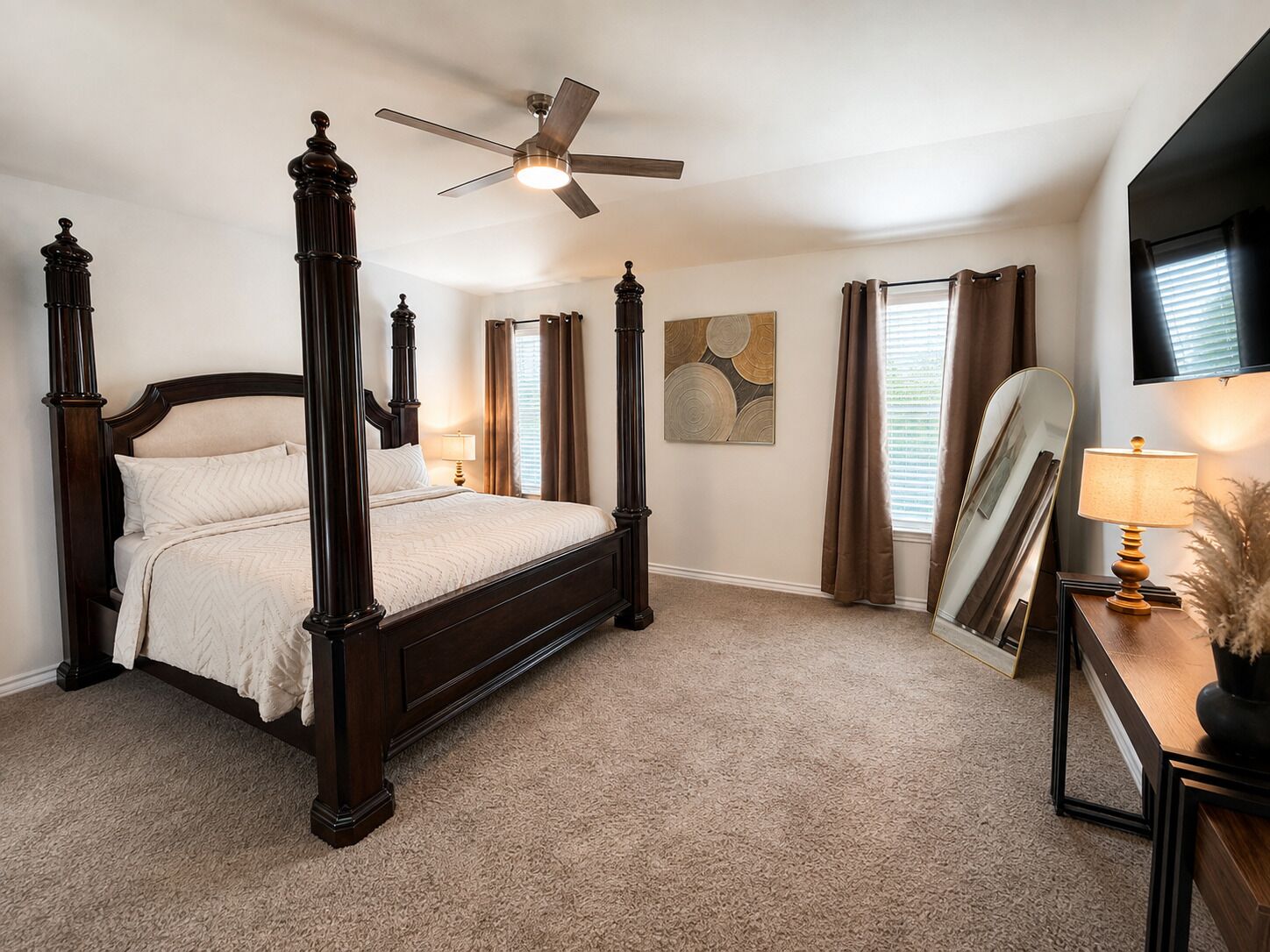 Ein Bett mit Himmelbett, ein Deckenventilator, ein Nachttisch mit Lampe und ein großer Spiegel.