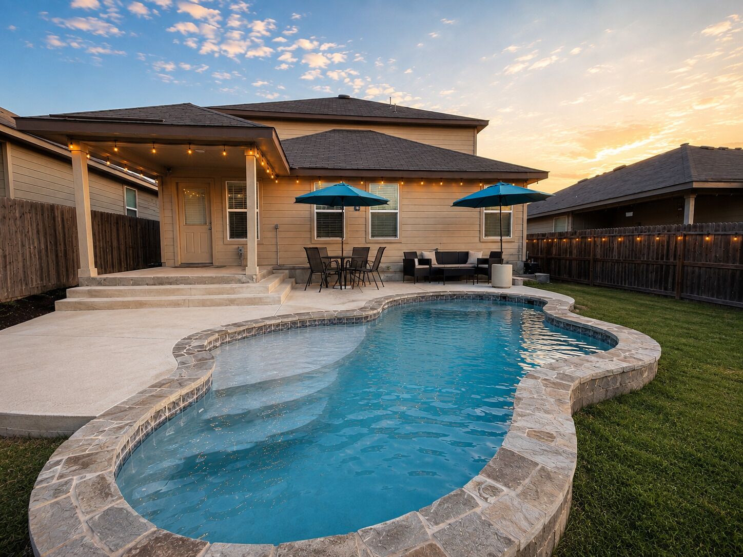 A residential property with a swimming pool, outdoor seating, and a covered patio area.
