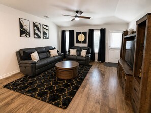 A living room with two sofas, a coffee table, and a ceiling fan. - Pool Retreat - 5BR - Sleeps 16+ - Lackland AFB (San Antonio)