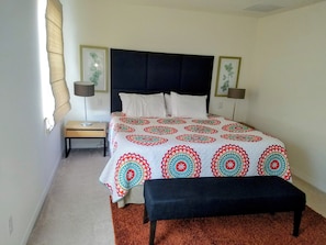 A bedroom with a bed, two bedside tables, a bench, and two wall-mounted lamps. - Beautiful family home close to all attractions. (Kissimmee)