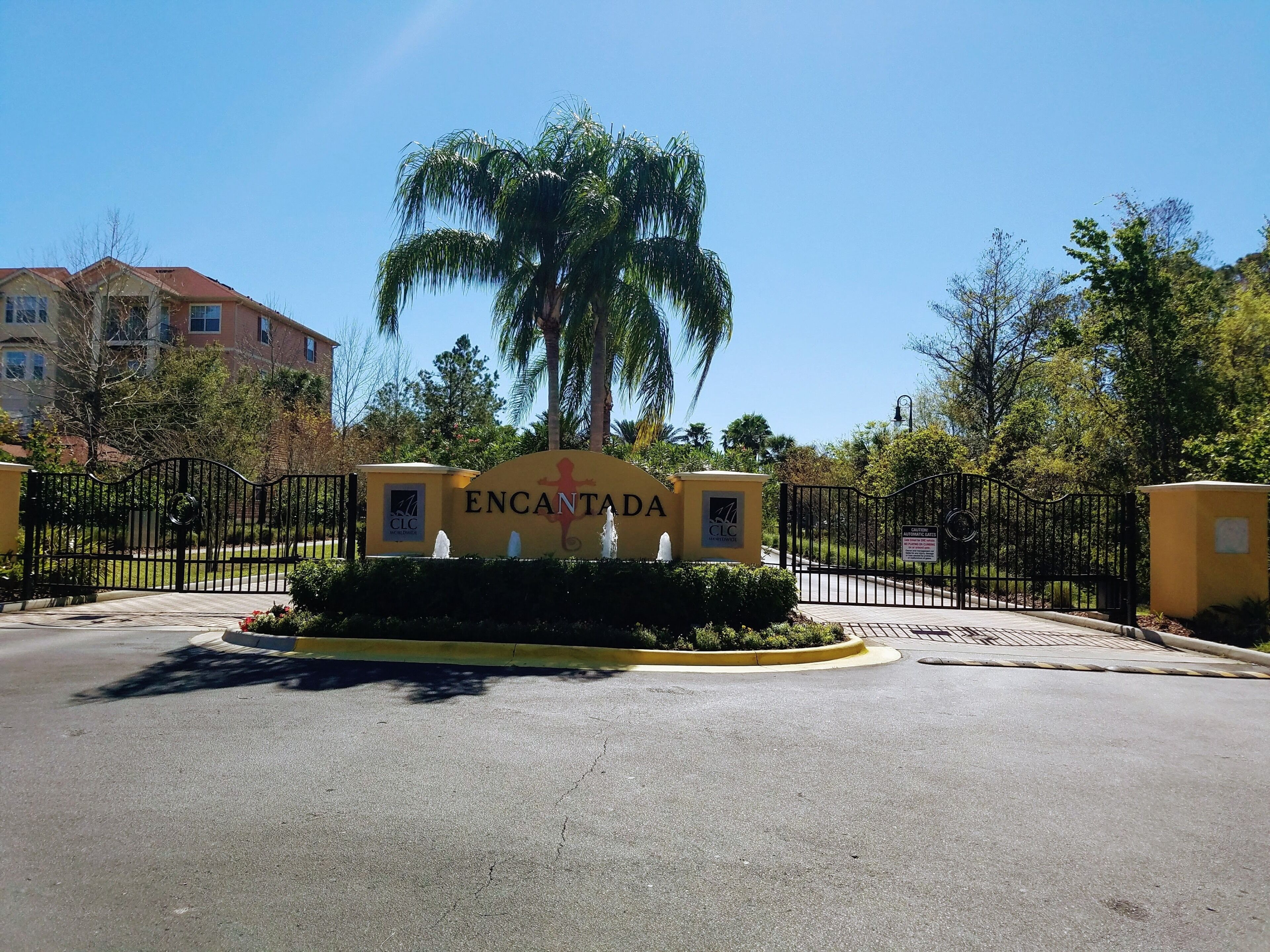 A gated entrance with a sign reading 'ENCANTADA' and a palm tree in the background.
