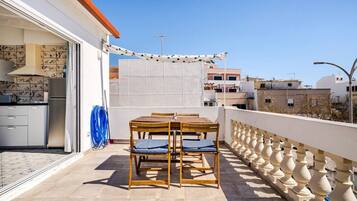 Un balcón con mesa y sillas, vistas de la ciudad y una zona de cocina.
