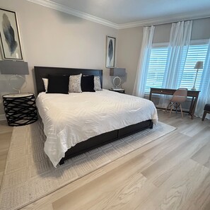 A bedroom with a large bed, two bedside tables, a chair, and a window with curtains. - Modern 1BR Beachfront Condo & Beautiful Courtyard Pool - D43 Orange Beach AL (Orange Beach)