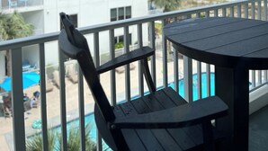 Ein Balkon mit Blick auf einen Strand und ein weißes Gebäude.