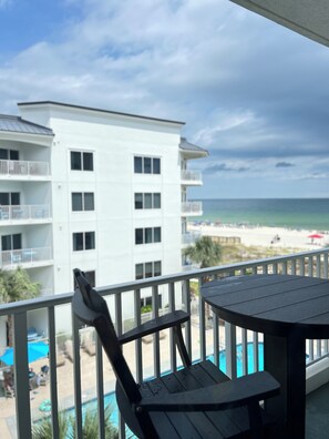 Ein Balkon mit Blick auf einen Strand und ein weißes Gebäude.