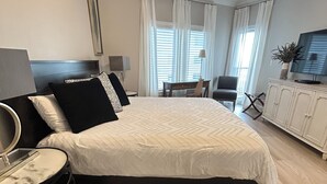 Ein Hotelzimmer mit Bett, Schreibtisch, Stuhl, Fernseher und Pflanze.