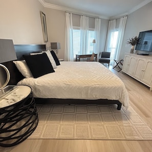 Ein Hotelzimmer mit Bett, Schreibtisch, Stuhl, Fernseher und Pflanze.
