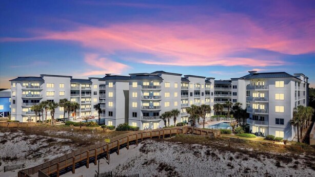 Ein mehrstöckiges Hotel mit Balkonen, einem Pool und Blick auf den Strand.