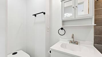A bathroom with a white toilet, a sink, and a mirror above it.