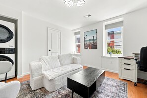 A modern living room with a white sofa, a black coffee table, and a patterned rug. - Private 1-bed apartment w/ full kitchen & laundry in University City (Philadelphia)