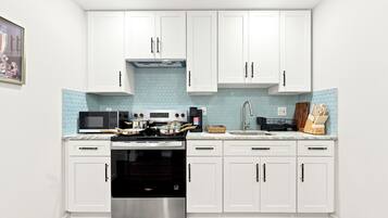 A kitchen with white cabinets, a stainless steel stove, a microwave, and a sink.