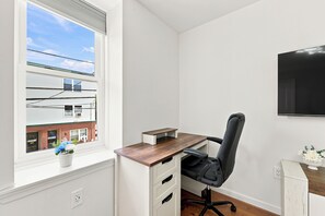 A room with a desk, chair, and a TV mounted on the wall. - Private 1-bed apartment w/ full kitchen & laundry in University City (Philadelphia)