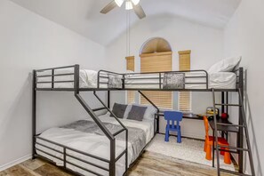 A bunk bed room with a desk and chair, a ceiling fan, and a window with blinds. - Family Retreat • King Suite • Sleeps 11 • Game Room • Near SeaWorld & Lackland (San Antonio)