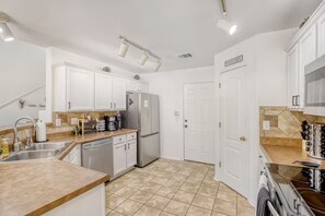 A kitchen with white cabinets, a stainless steel refrigerator, and a tiled floor. - Family Retreat • King Suite • Sleeps 11 • Game Room • Near SeaWorld & Lackland (San Antonio)