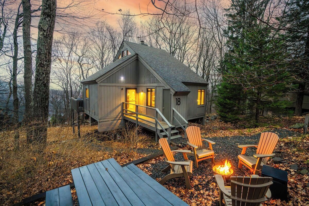 A cabin with a deck, outdoor seating, and a fire pit.