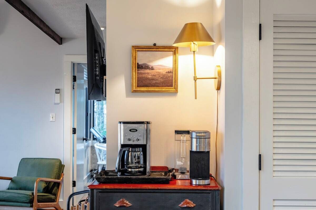 Ein Zimmer mit Kaffeemaschine, einer Lampe und einem gerahmten Bild an der Wand.