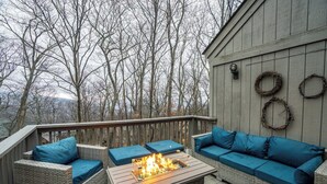 A deck with wicker furniture, a fire pit, and a view of trees. - Walk to SKi Slopes  and Hot Tub (Wintergreen Resort)