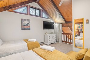 Ein Schlafzimmer mit zwei Betten, einem Fernseher, einem Schminktisch und einem Spiegel.