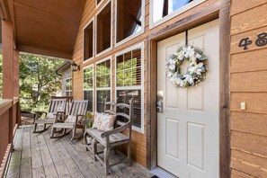 A wooden porch with rocking chairs and a door with a wreath. - Private Lodge near Silver Dollar City_Ramp Entry_Overlooks Golf Course_Free Attraction Tickets (Branson West)