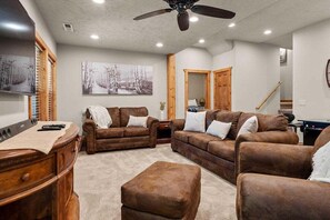 Ein Wohnzimmer mit Deckenventilator, zwei Sofas, einem Couchtisch und einem Holzkabinett.